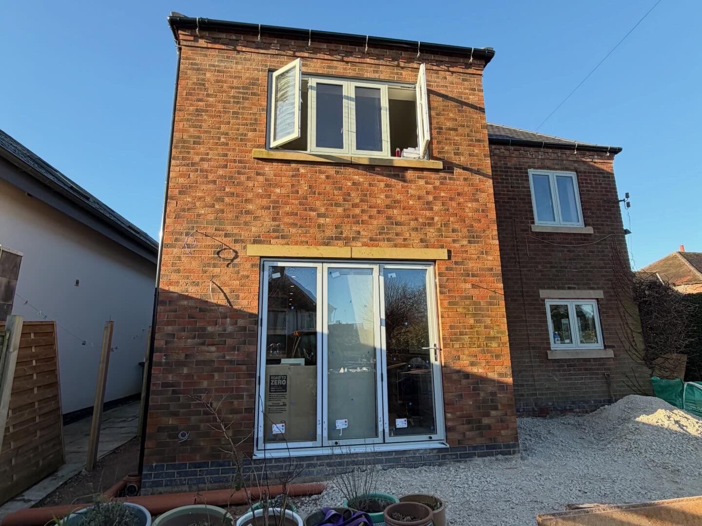 Two storey red brick rear extension with new window openings and bifold doors