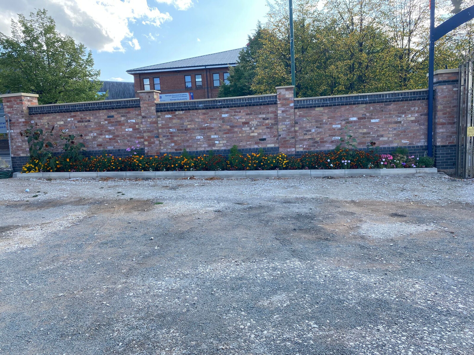 Long brick boundary wall with piers, blue brick plinth and dentil course to a school site
