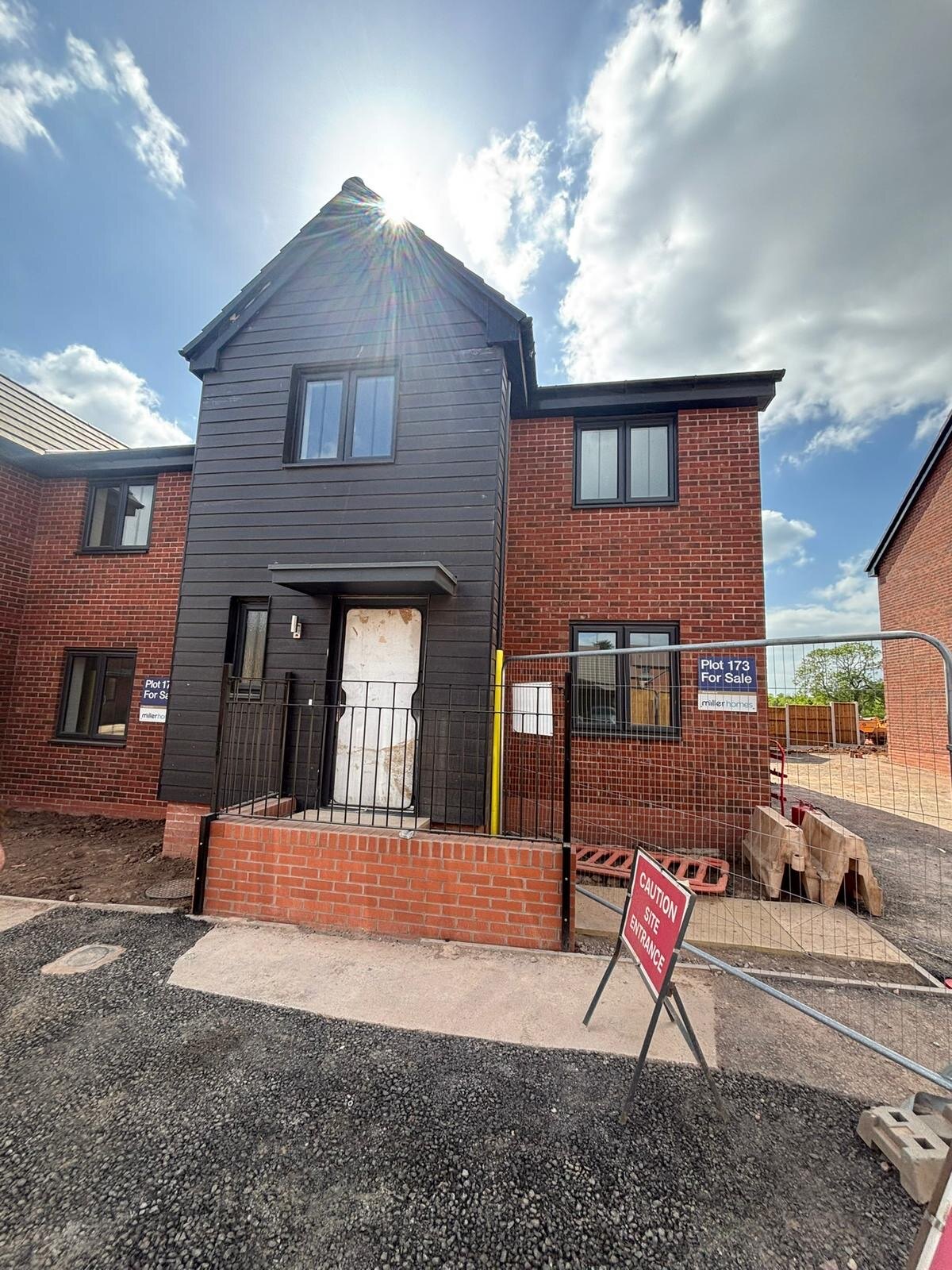 New build townhouse with red brick elevations, dark cladding and a brick retaining wall