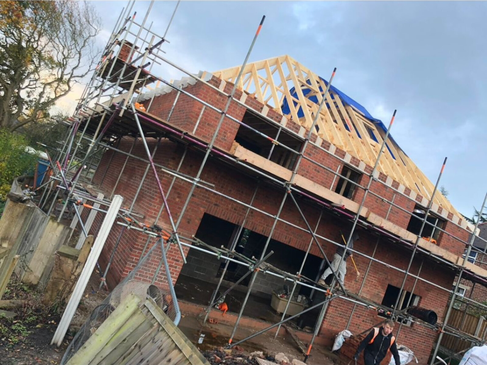 New build house in red brickwork at roof truss stage with full scaffold