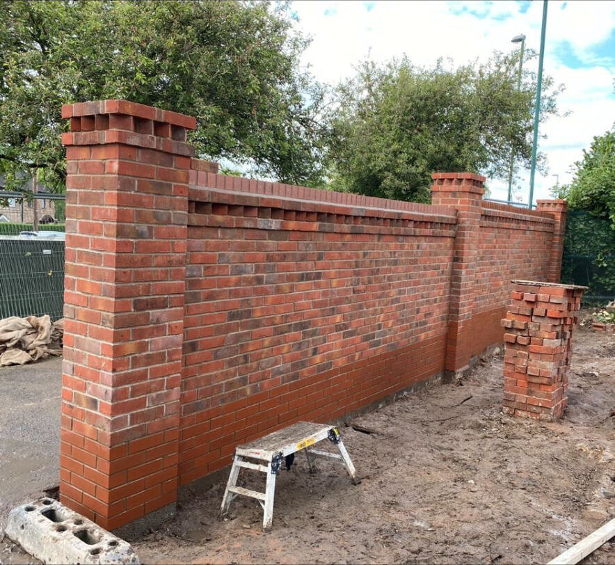 New red brick boundary wall with brick piers and saddleback coping