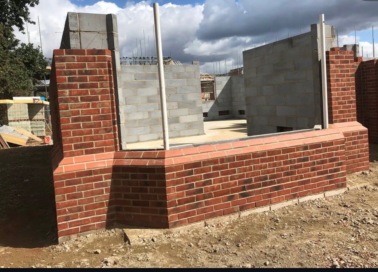 Curved red facing brickwork and blockwork elevations under construction on a new build plot