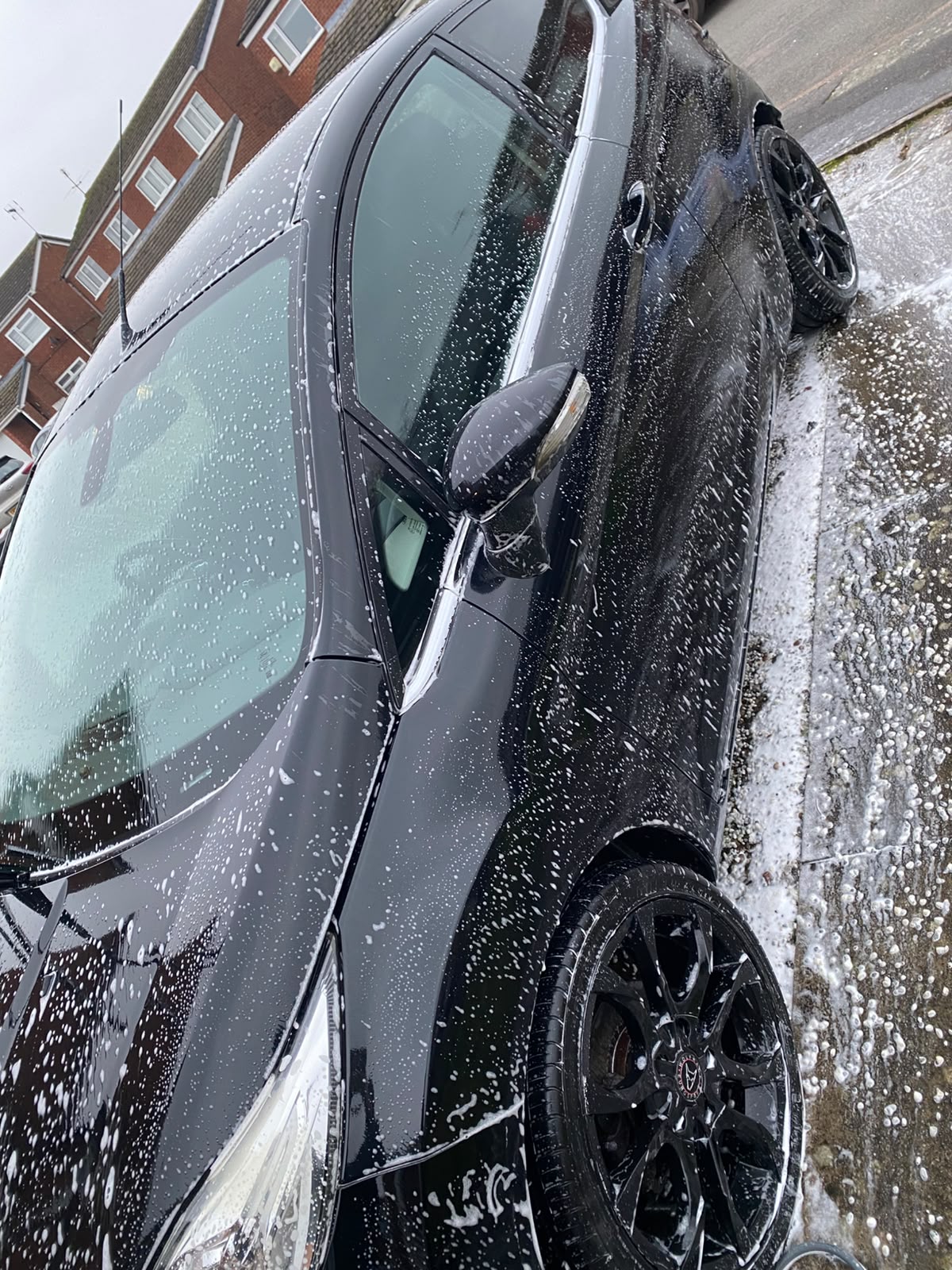 Snow foam pre-wash covering a black car