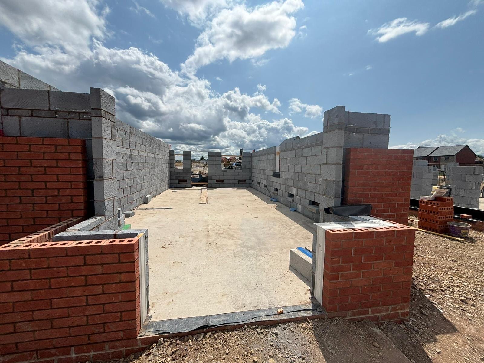 New build plot with blockwork inner leaf and red facing brickwork rising from the floor slab