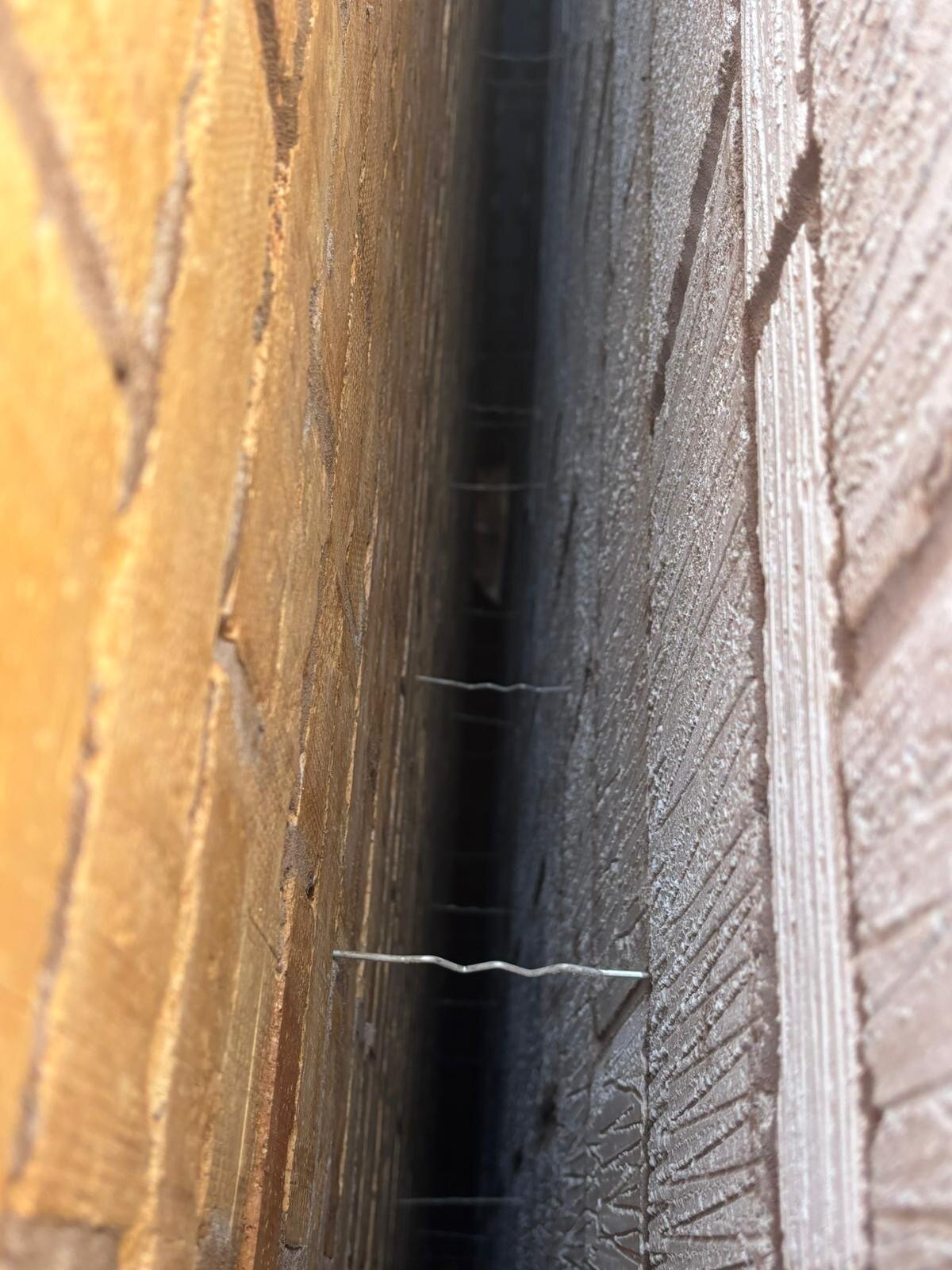 Close up of cavity wall construction showing wall ties between brick and blockwork