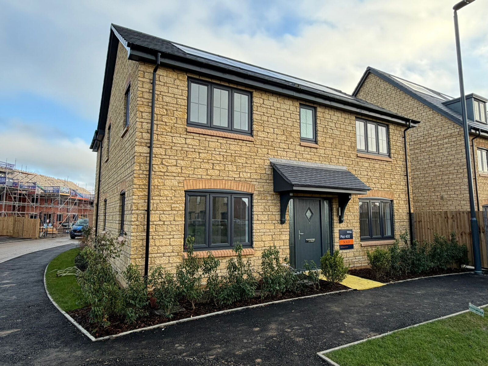 Completed detached new build in reconstituted stone with brick arches and landscaped frontage