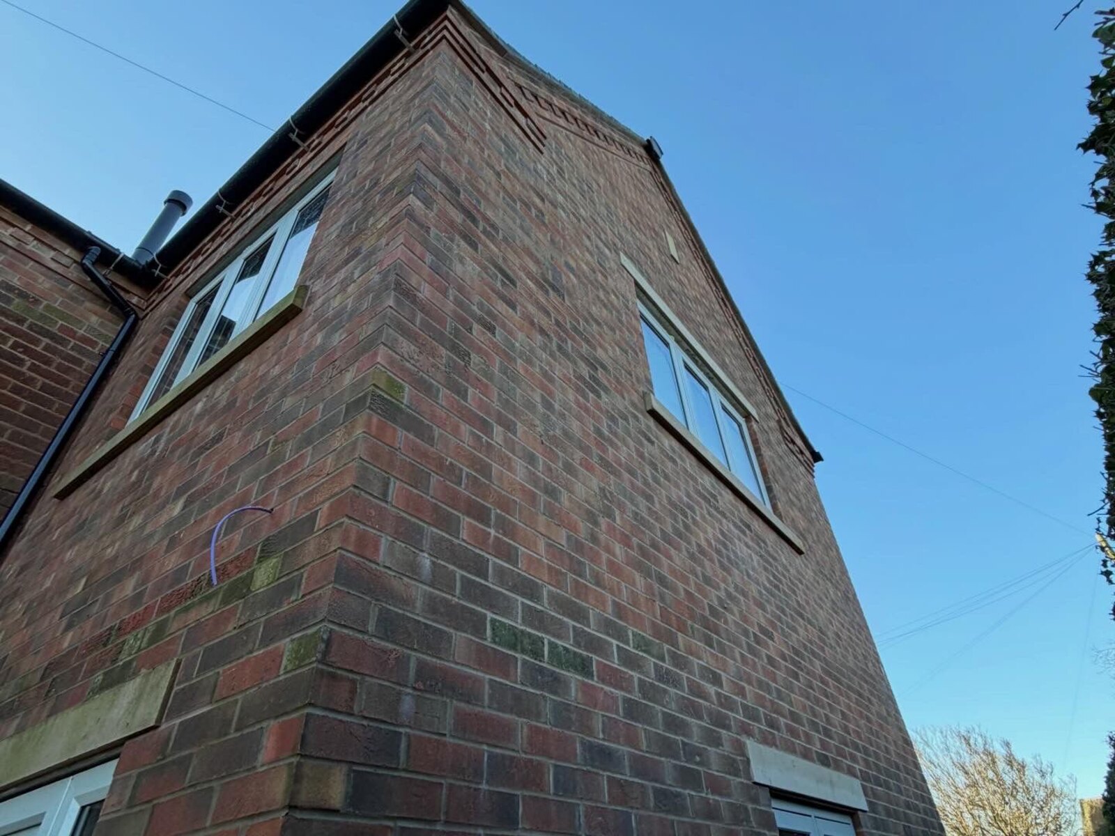 Brick gable elevation with dentil corbel detailing and stone cills on a renovated property