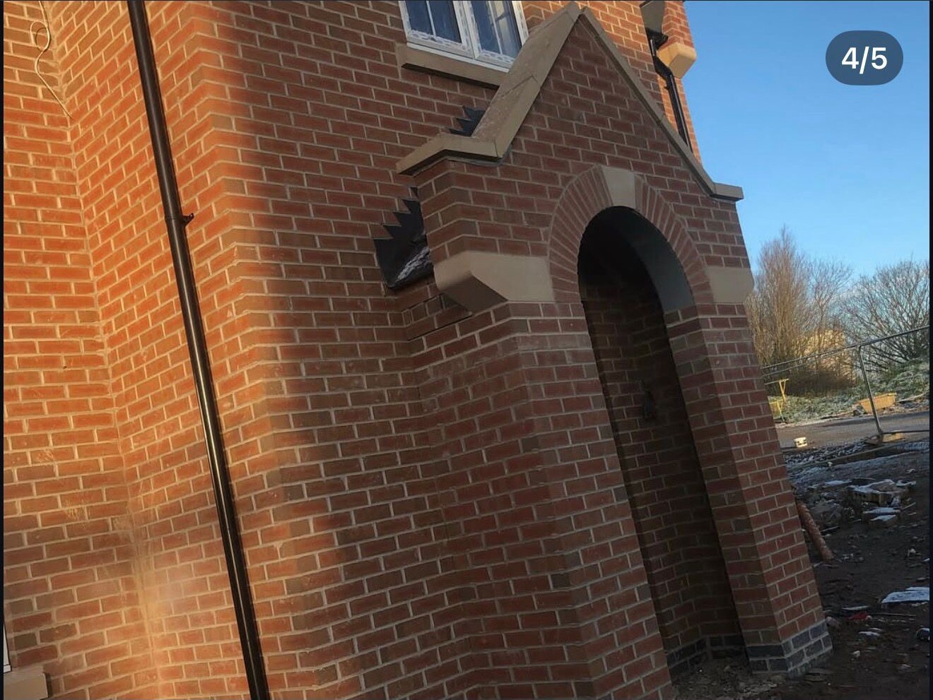 Brick arched entrance porch with stone detailing and dentil brick courses on a new build home
