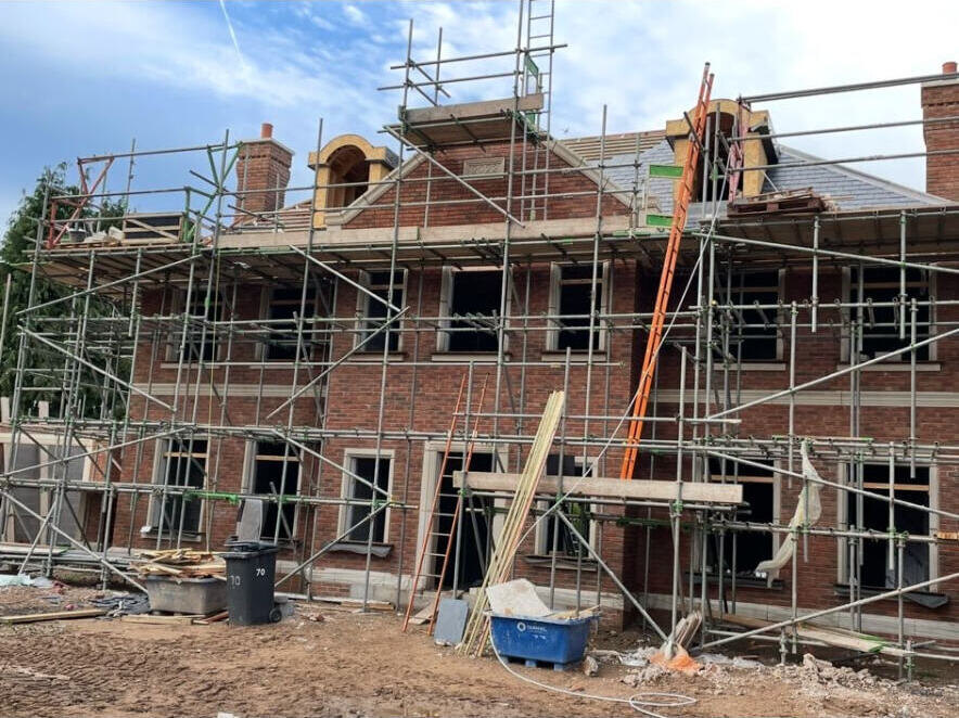 New build housing plots under construction with scaffolding and brick and block elevations