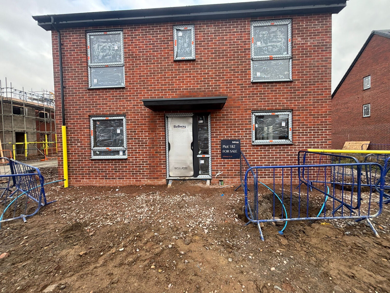 New build Bellway house frontage in red brickwork with brick soldier course over the entrance door