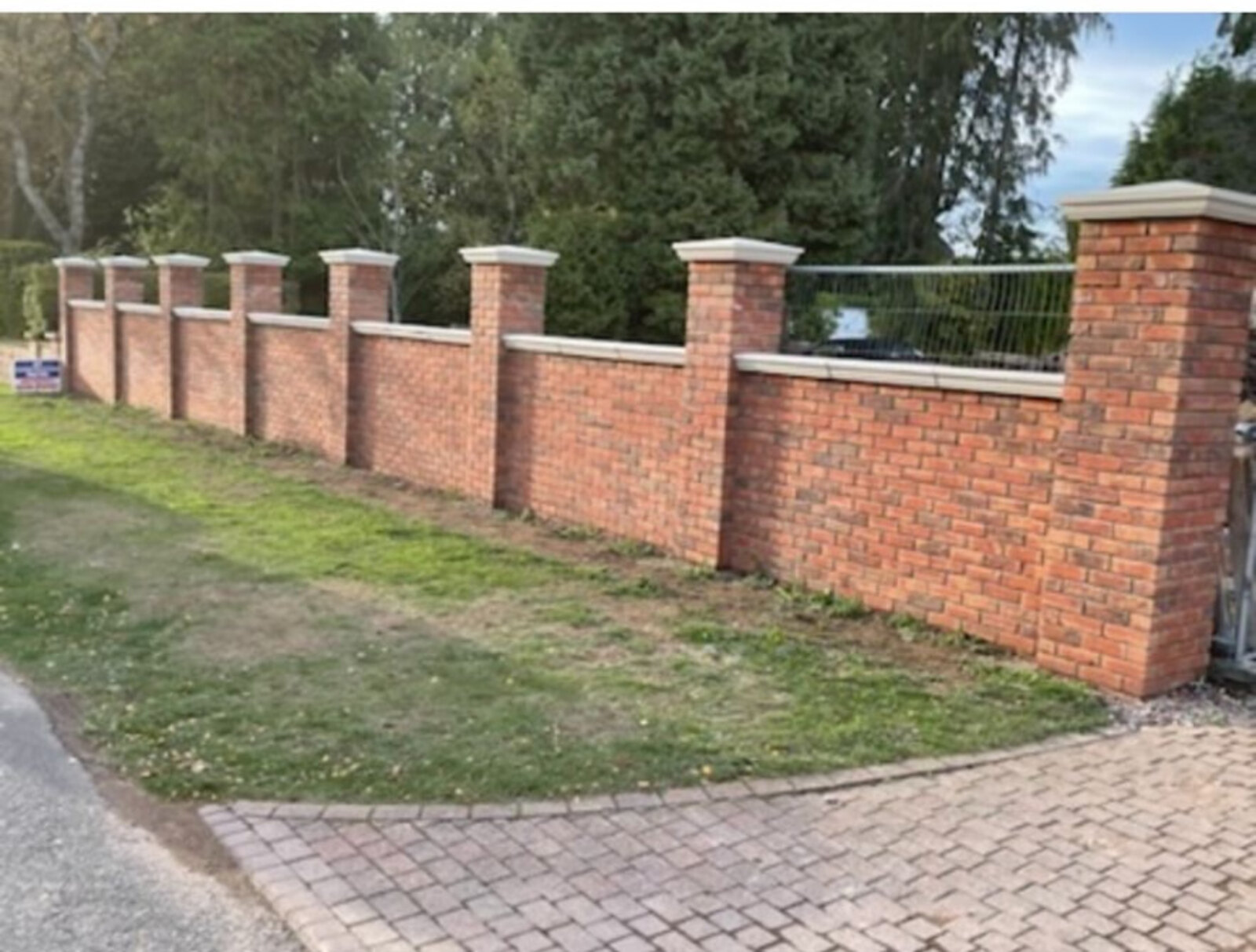 Newly built stone boundary wall with brick plinth and coping