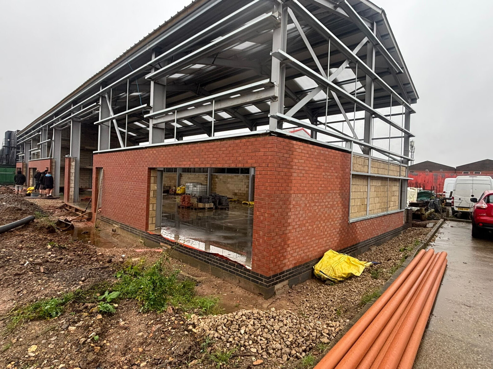 Commercial unit corner in red facing brickwork with blue brick plinth and steel portal frame above