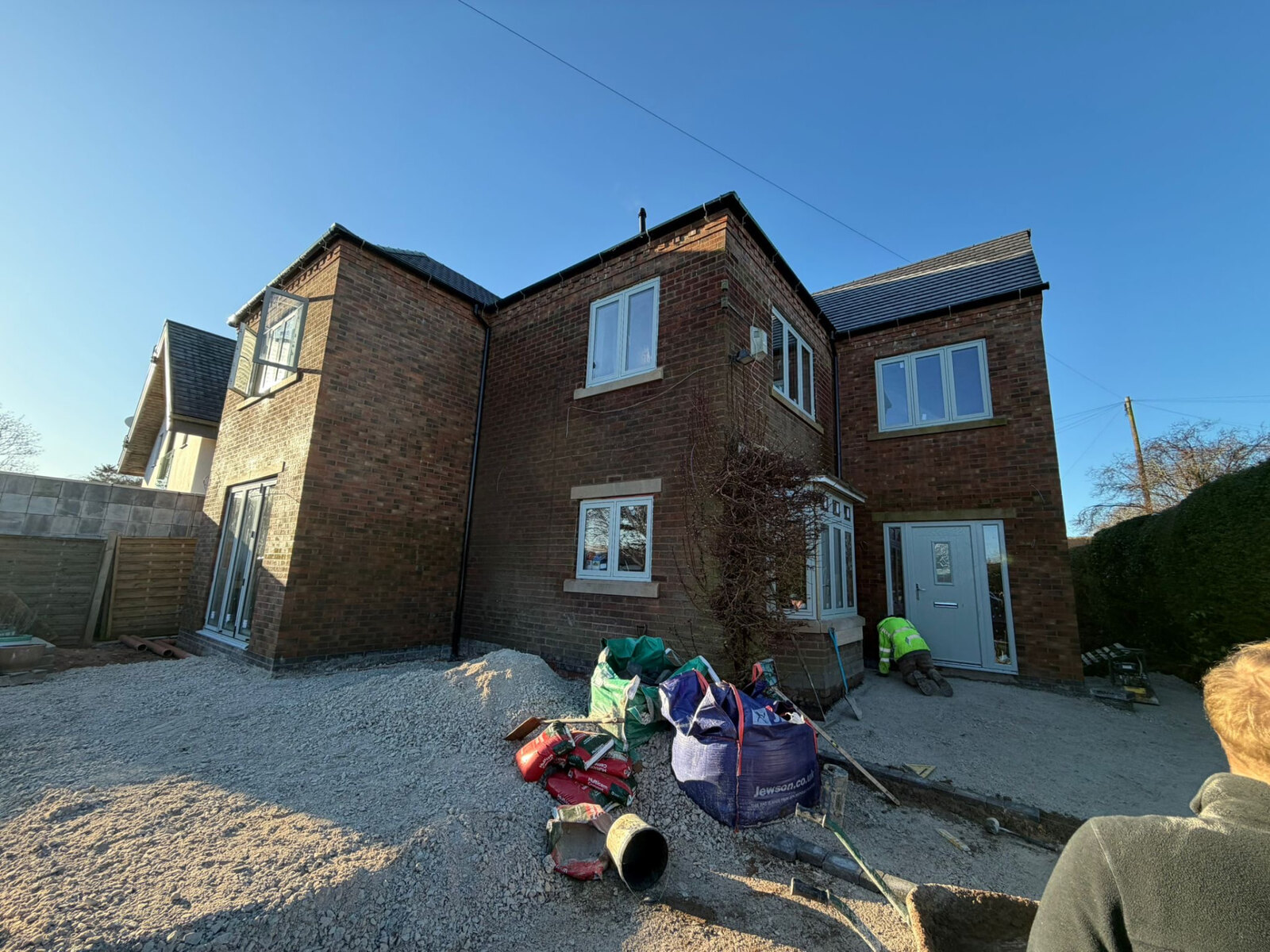 Detached new build house in red brickwork with stone cills viewed from the rear garden