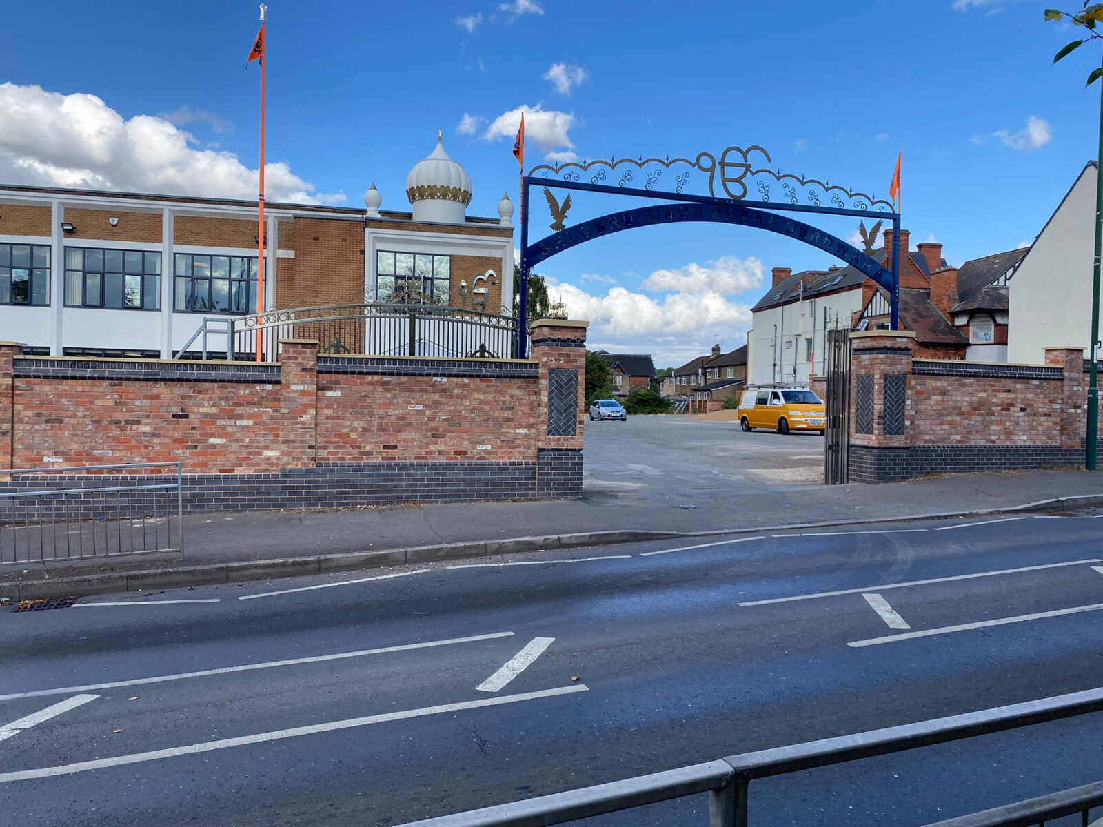 Completed brick boundary wall with blue brick detailing and decorative gateway to a Gurdwara